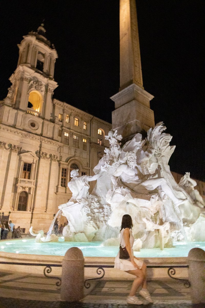 Devant une fontaine de la place Navone le soir
