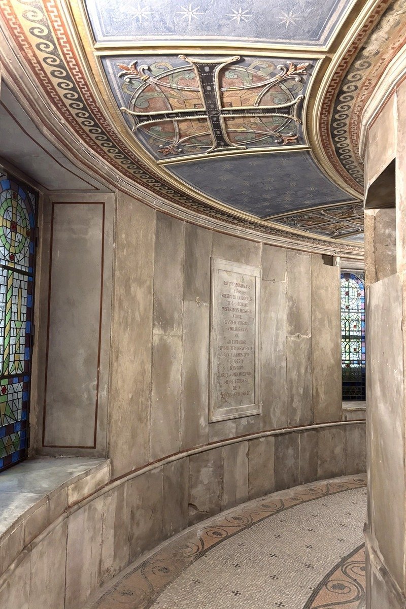 Abside en pierre avec plafond peint doré, vitraux colorés et inscription latine