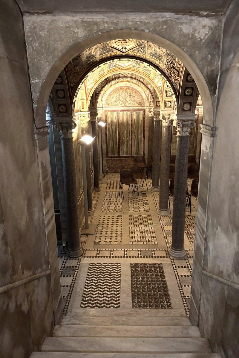 Vue en plongée d'une crypte ancienne avec colonnes et sol en mosaïque