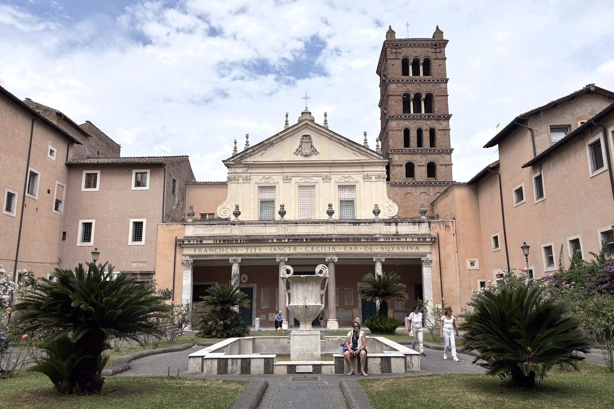 Façade baroque d'une basilique avec clocher roman et cour intérieure verdoyante