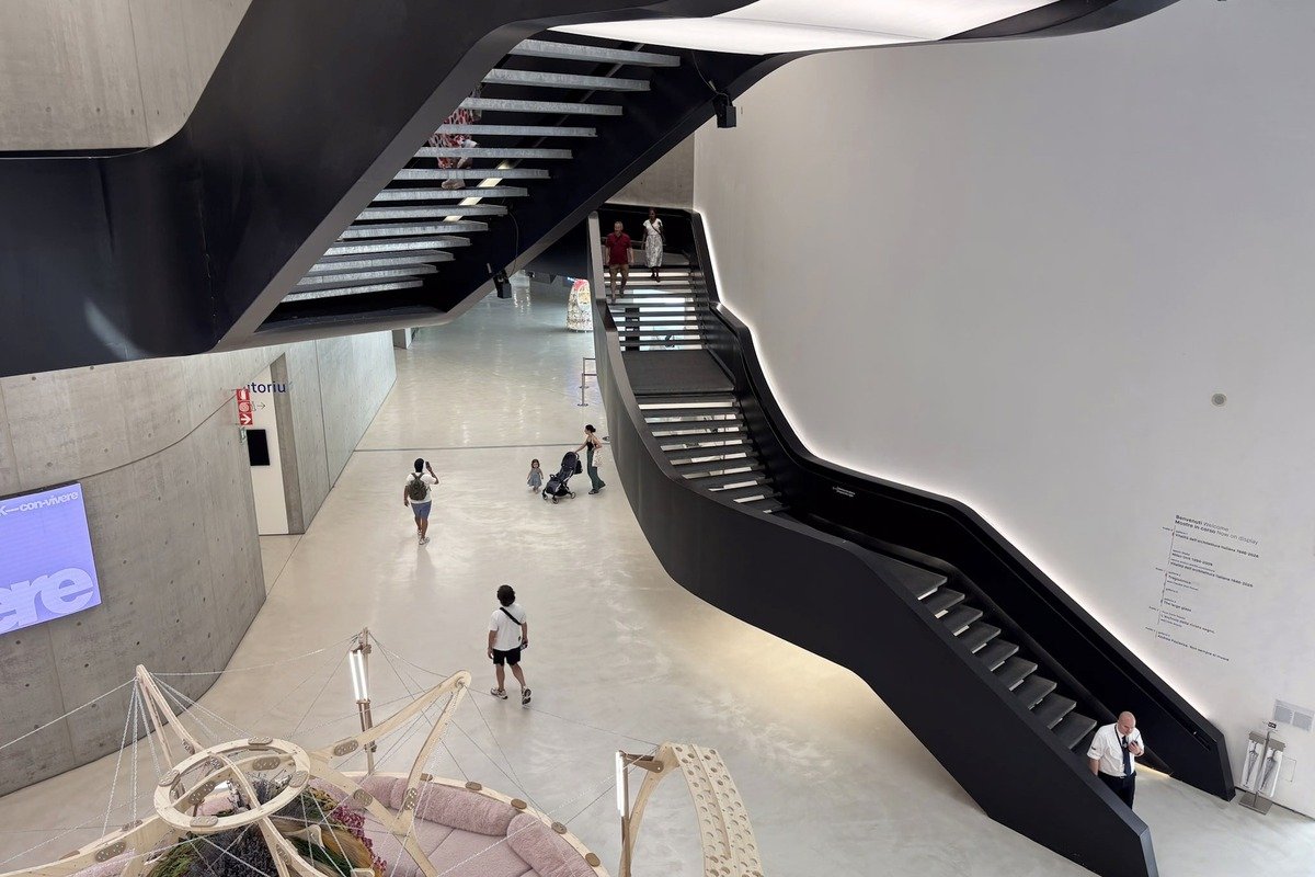 Atrium de musée contemporain avec escalier noir et visiteurs