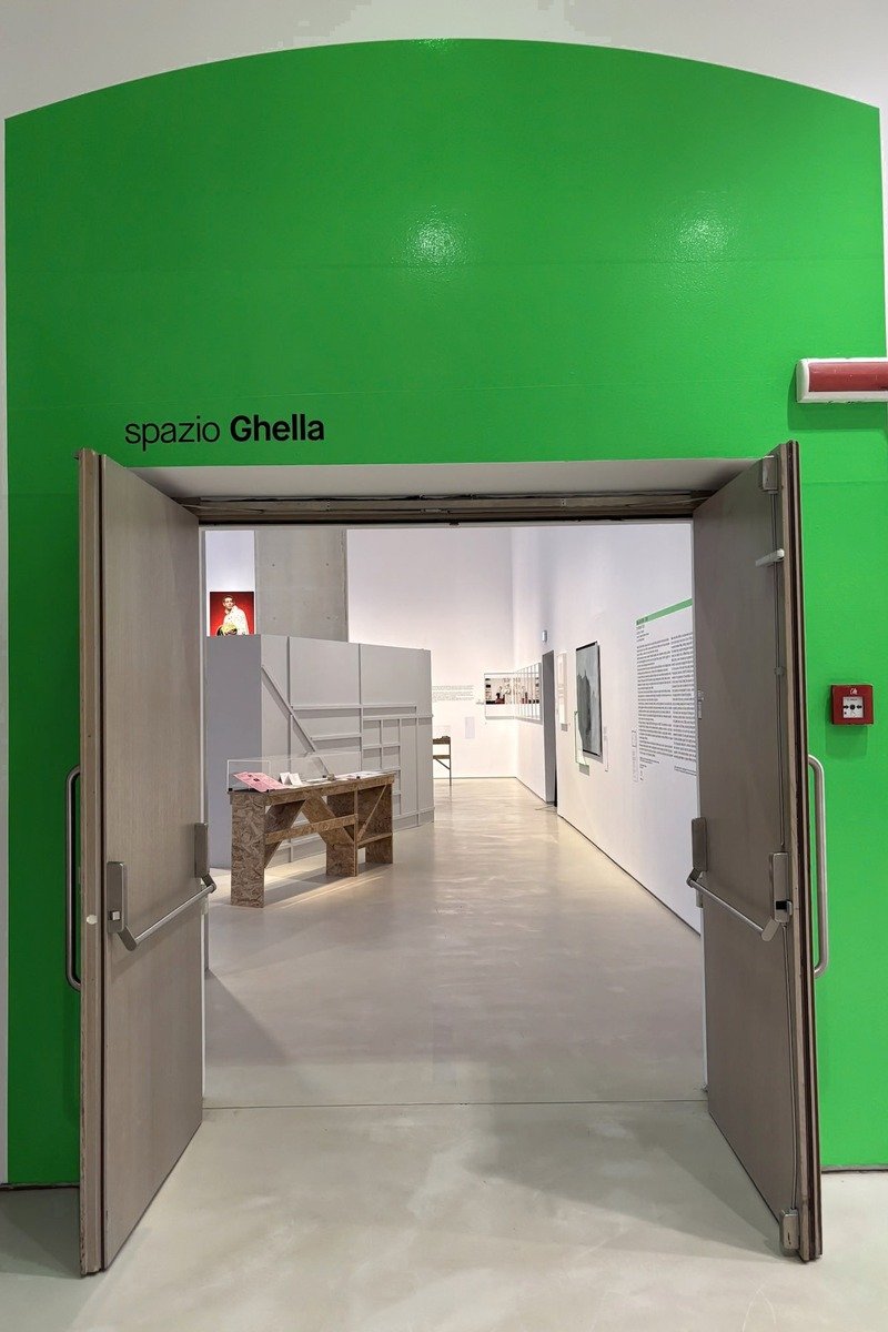 Entrée d'une salle d'exposition avec large mur vert vif et portes ouvertes