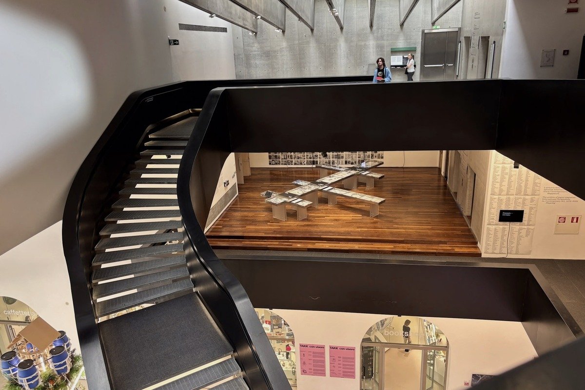 Escalier courbé noir surplombant une galerie d'art contemporain sur plusieurs niveaux
