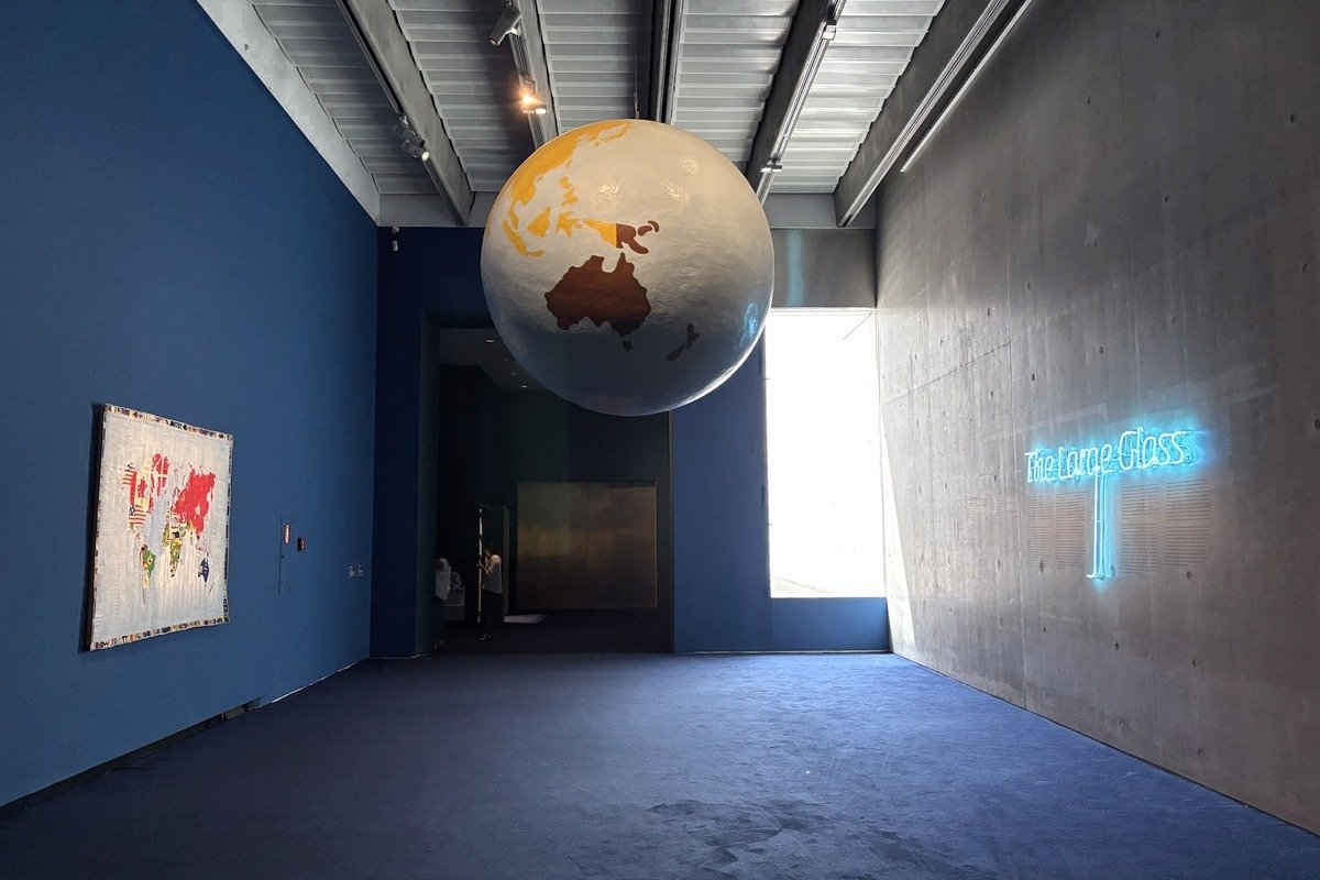 Globe terrestre suspendu dans une galerie avec inscription néon bleue