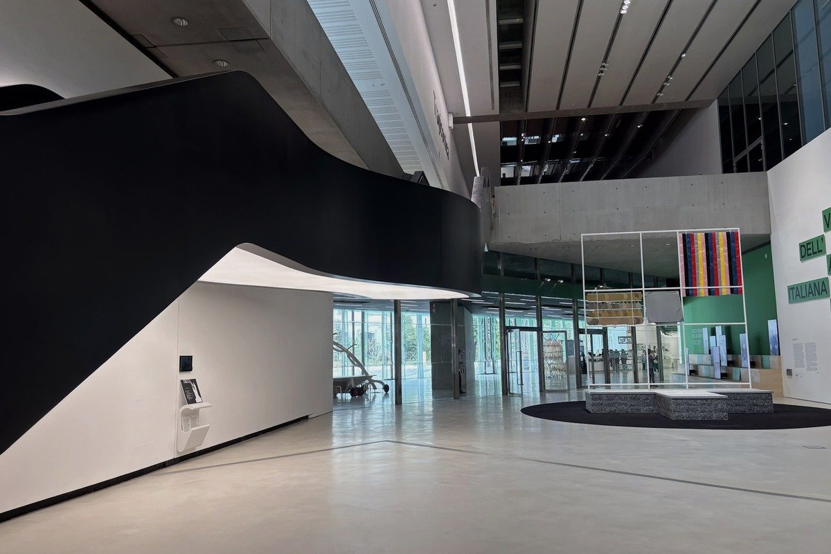 Hall de musée contemporain avec cloison courbe noire et exposition