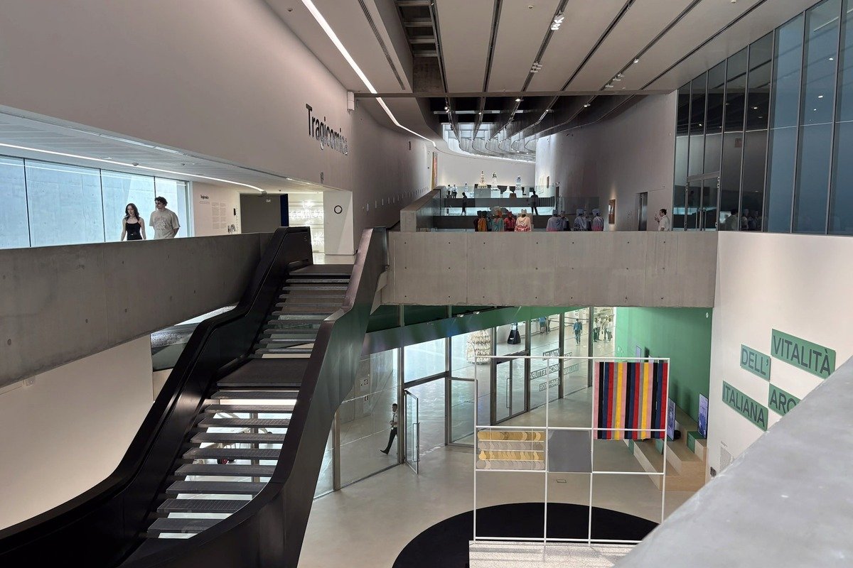 Intérieur de musée contemporain avec escalier noir et galeries sur plusieurs niveaux