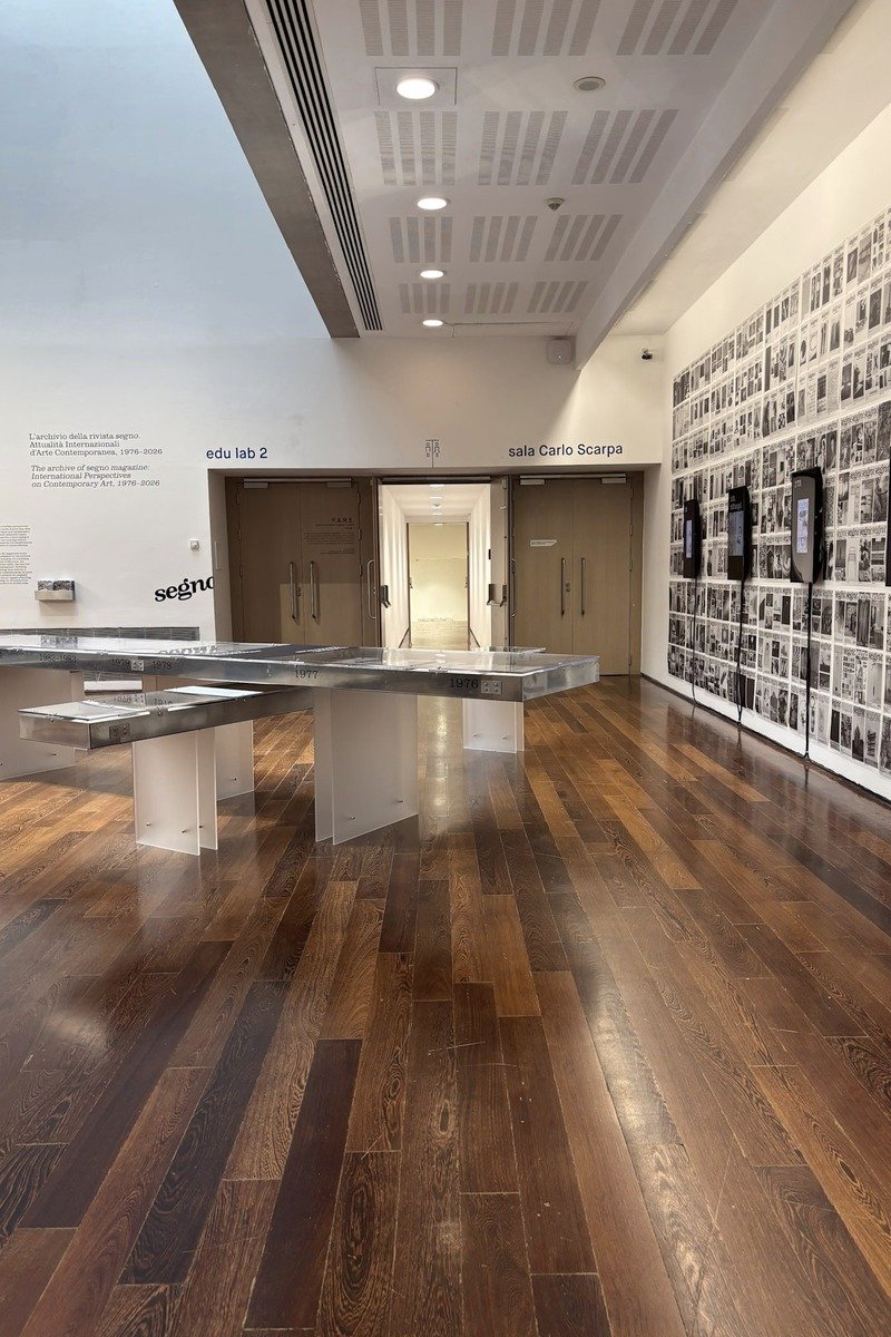 Salle d'exposition avec présentoirs en verre et parquet en bois sombre
