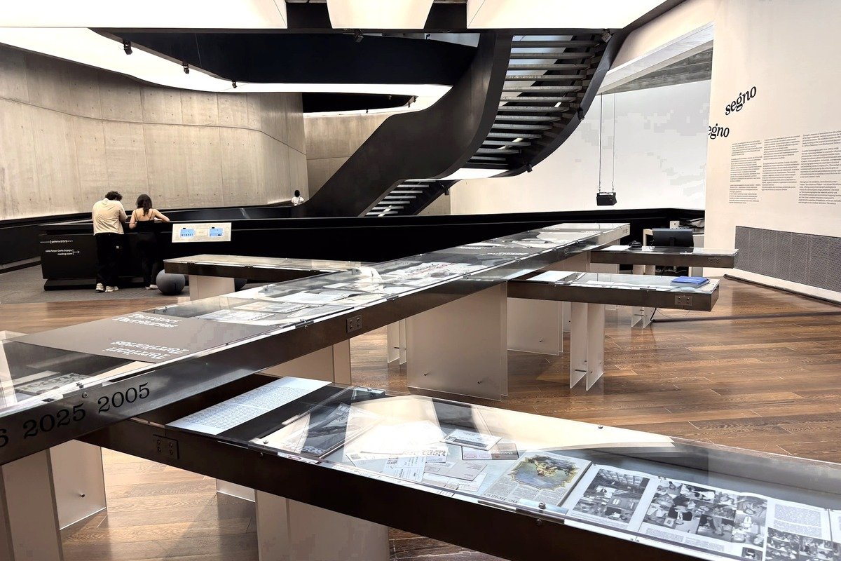 Salle de musée avec vitrines chronologiques et escalier noir en colimaçon