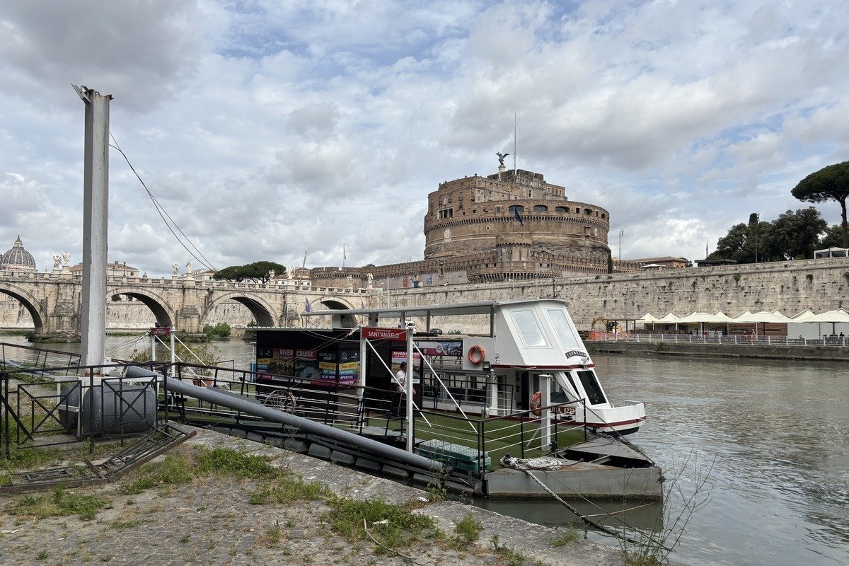 Péniche amarrée sur un fleuve devant un château cylindrique et un pont