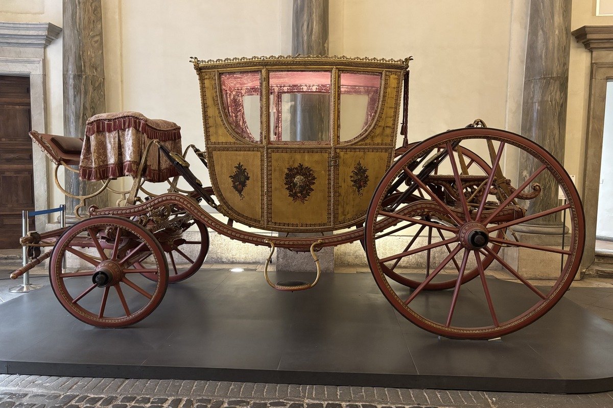 Carrosse d'apparat ancien aux roues rouges et caisse dorée exposé dans une salle