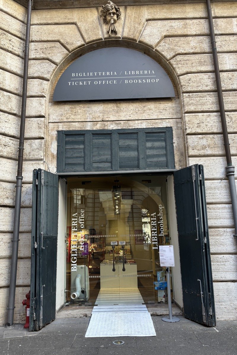 Entrée d'une librairie-billetterie encadrée de portes noires ouvertes