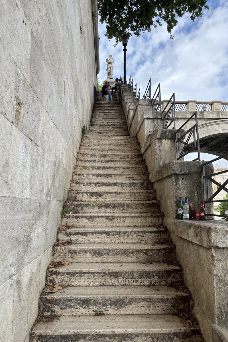 Escalier en pierre menant à un pont avec une statue au sommet
