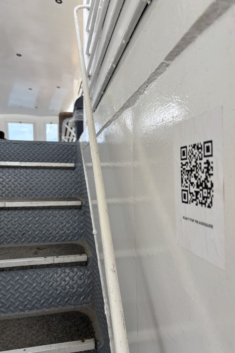 Escalier métallique antidérapant avec QR code audioguide sur mur blanc