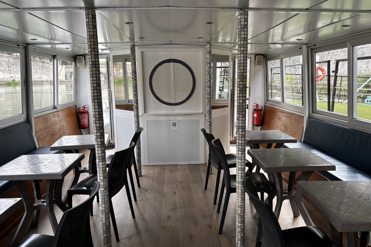 Salon intérieur d'un bateau avec tables et chaises noires