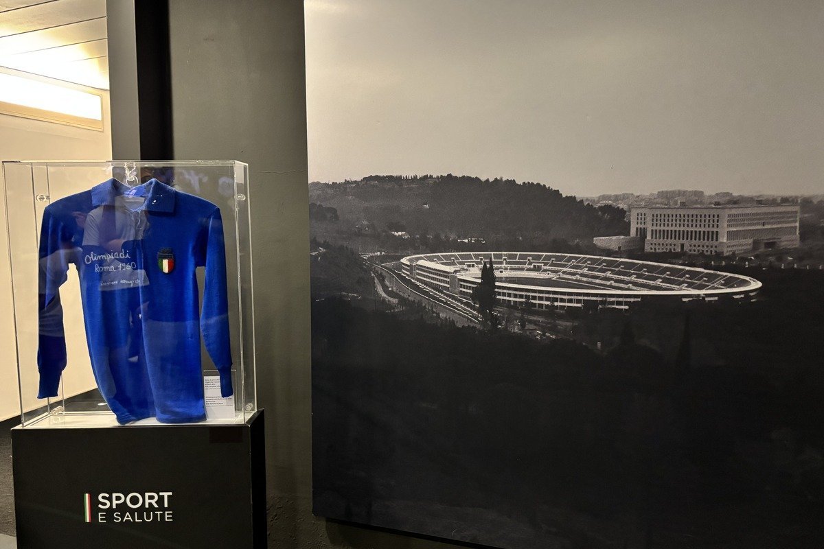 Maillot bleu italien sous vitrine devant une ancienne photo du stade olympique de Rome
