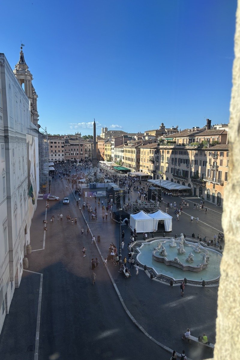 Vue en hauteur sur une grande place animée avec fontaine et obélisque