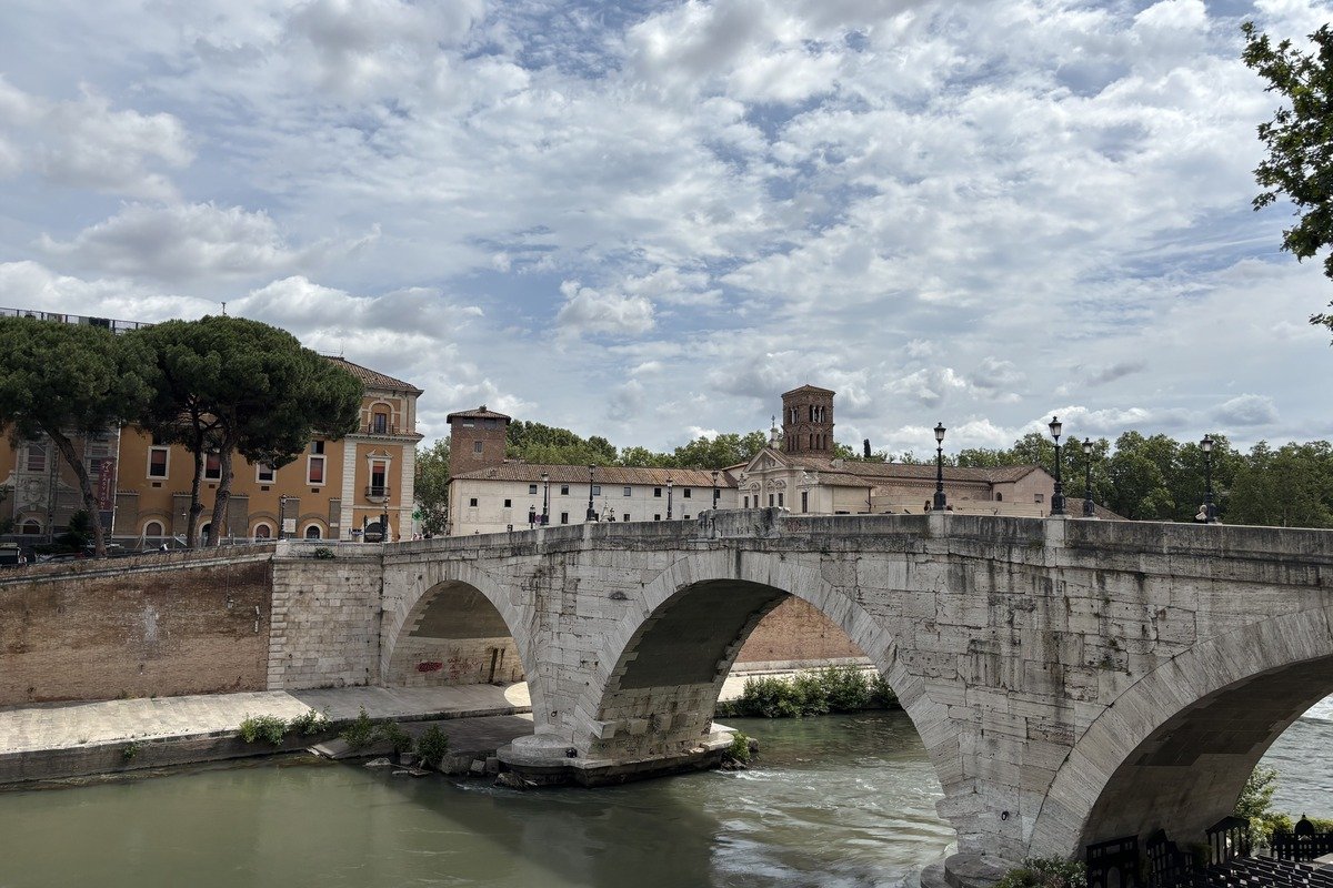 Ancien pont de pierre à trois arches enjambant une rivière verdâtre