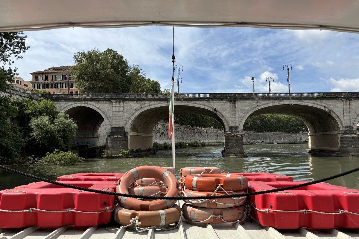 Proue d'un bateau avec bouées rouges face à un pont en pierre