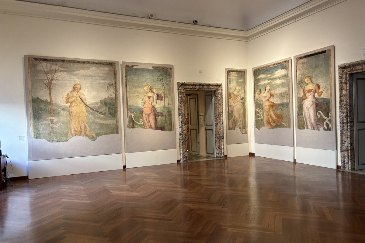 Salle de musée avec grandes fresques représentant des figures féminines drapées