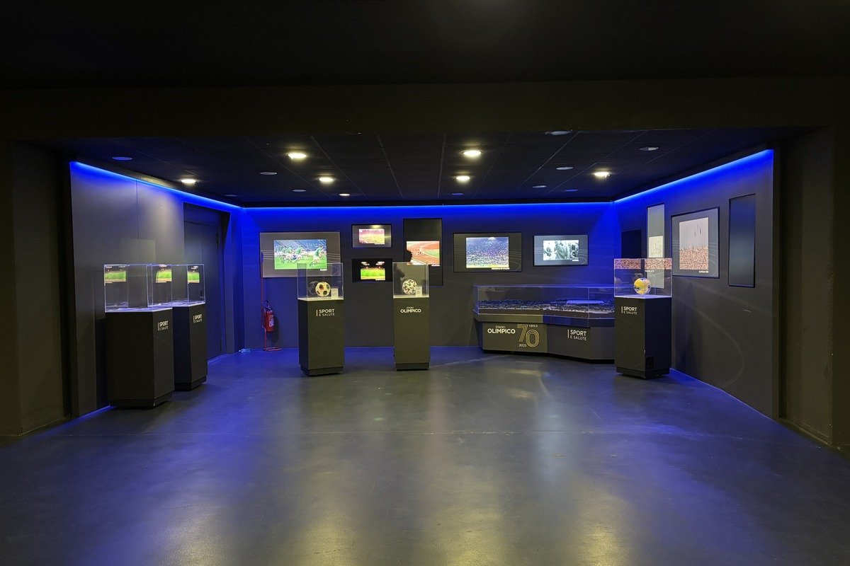 Salle d'exposition sombre avec vitrines, écrans et éclairage bleu