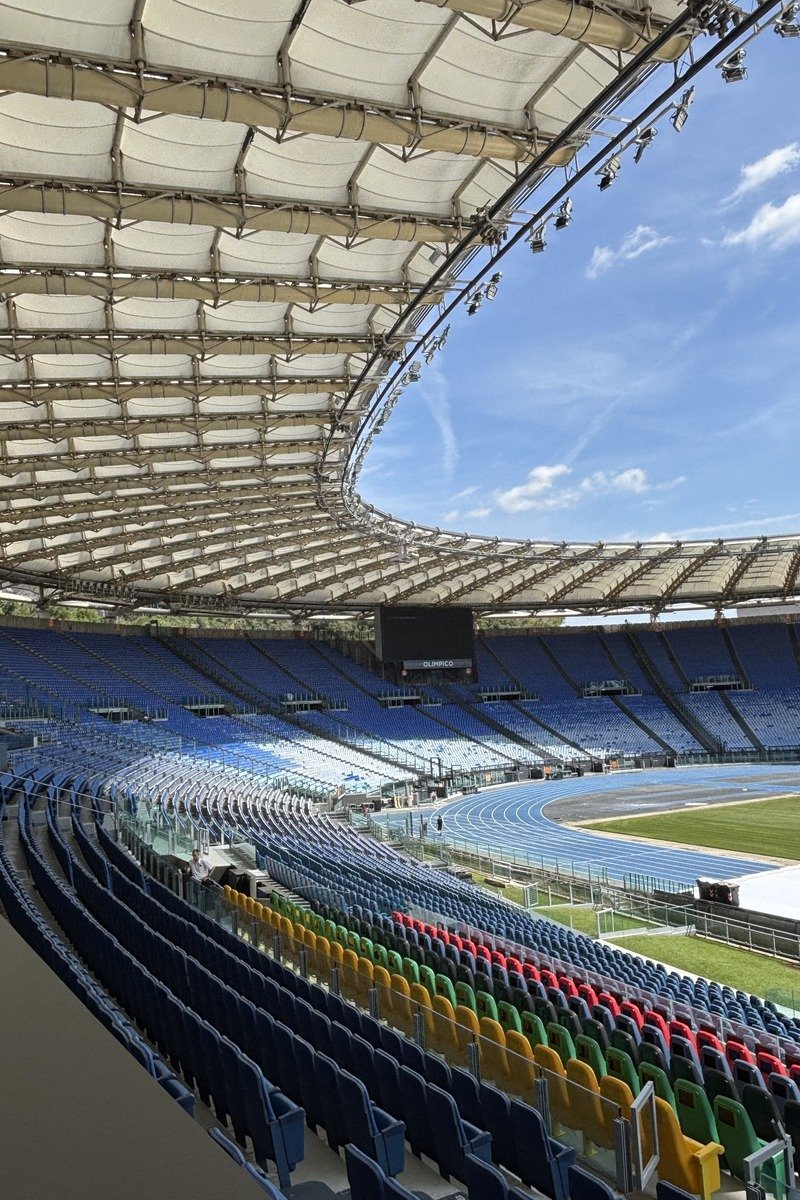 Tribune d'un grand stade avec sièges colorés et piste d'athlétisme bleue