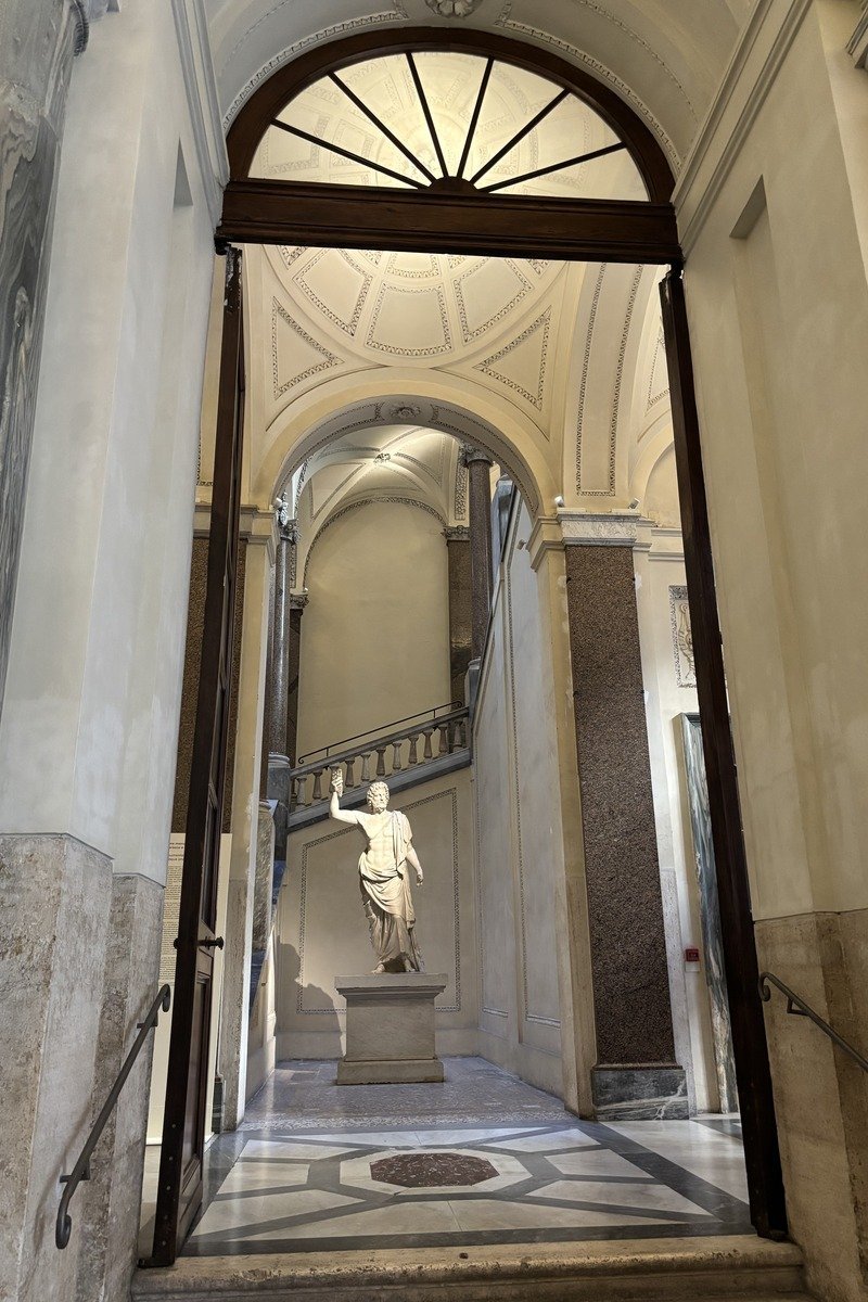 Vue en enfilade d'un couloir classique avec statue antique sur piédestal