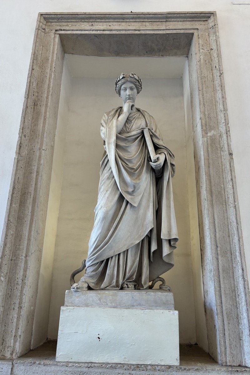Statue de marbre blanc d'une figure féminine drapée dans une niche