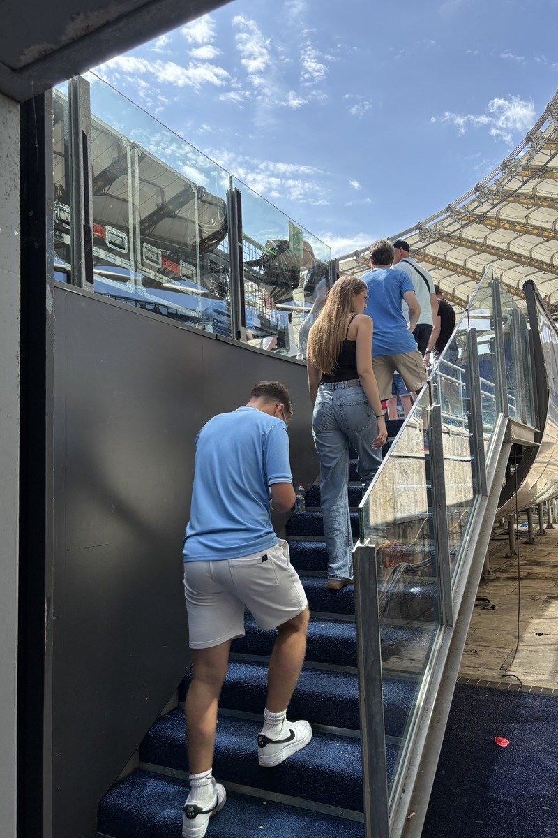 Supporters montant un escalier intérieur d'un stade par temps ensoleillé