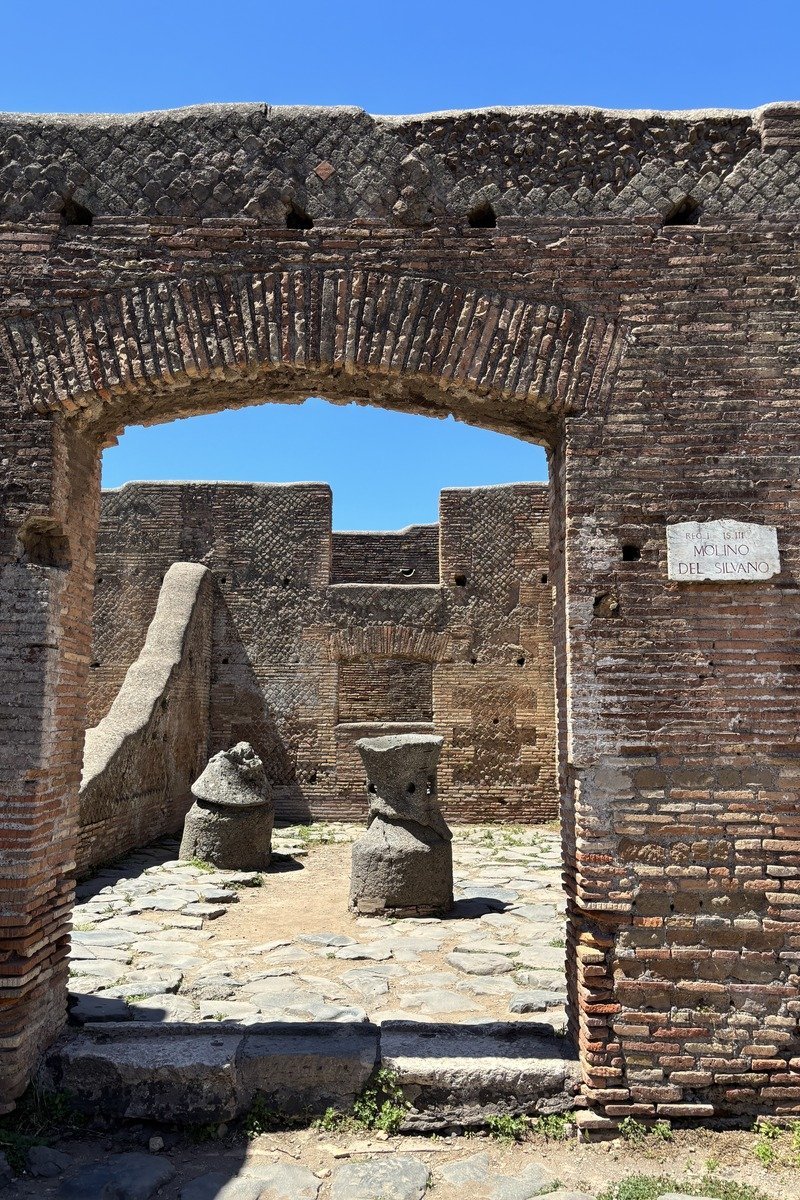 Arche en brique ancienne donnant sur des meules de pierre sous ciel bleu