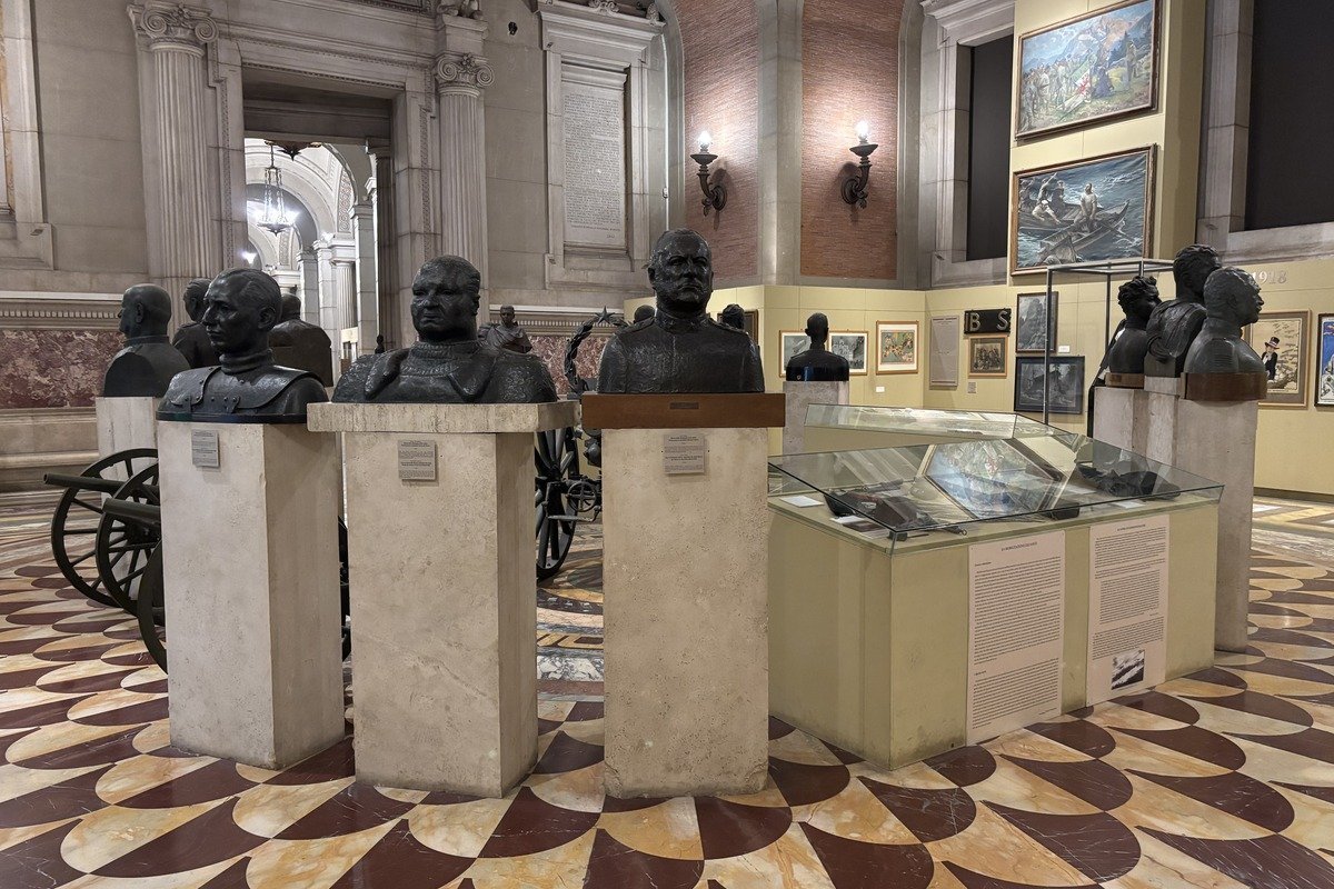 Rangée de bustes en bronze sur socles blancs dans une grande salle de musée