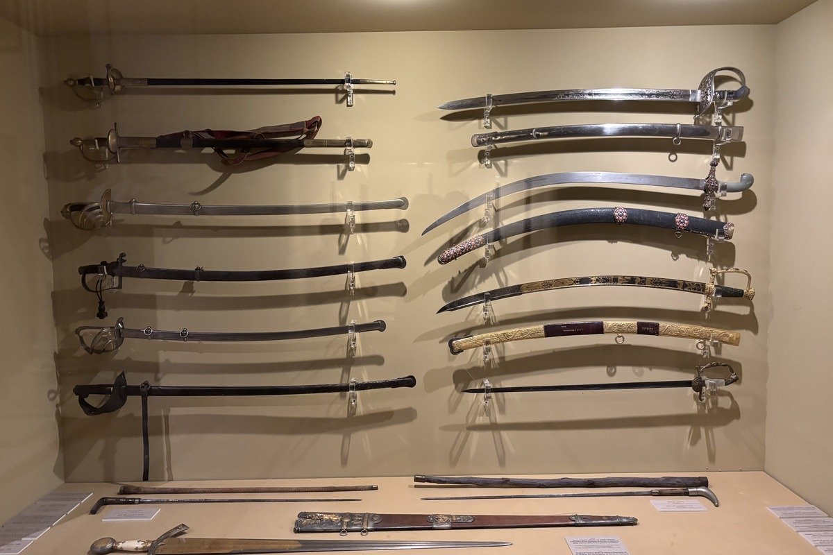 Collection d'épées et sabres anciens exposés sur un mur de musée