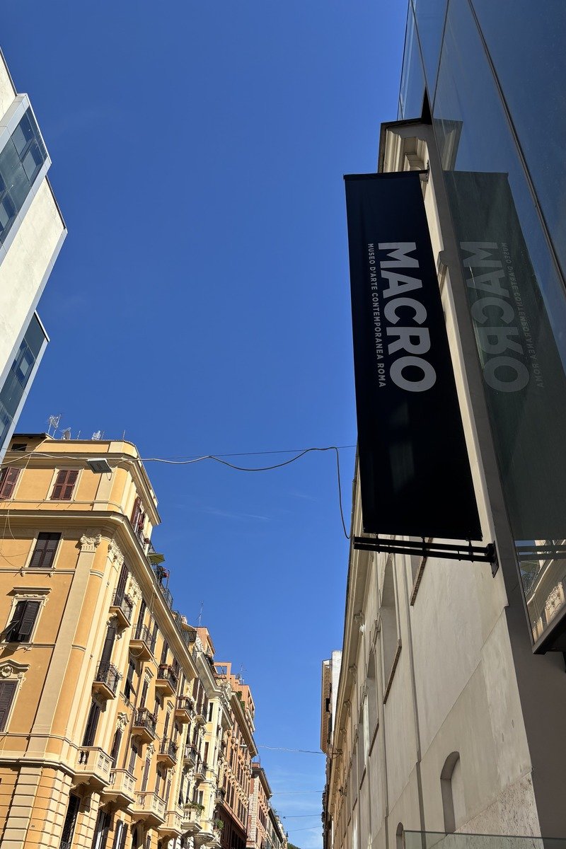 Enseigne noire d'un musée d'art contemporain entre immeubles haussmanniens et ciel bleu