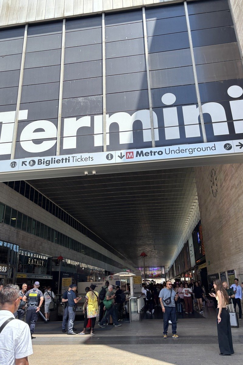 Entrée de la gare de Termini avec foule de voyageurs sous une façade noire