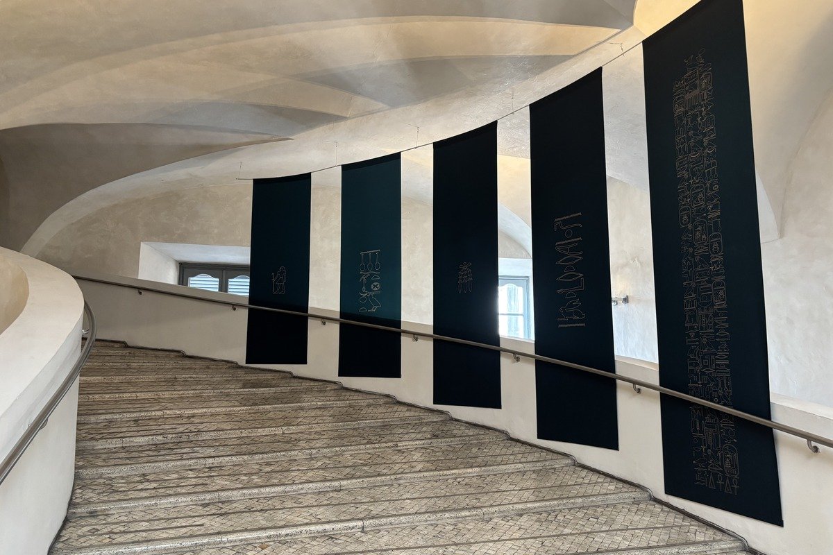 Grand escalier courbe avec bannières noires gravées sur mur blanc