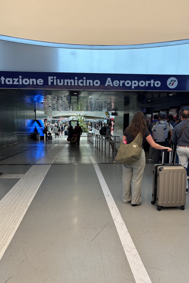 Voyageurs avec valises devant l'entrée de la gare de l'aéroport de Fiumicino