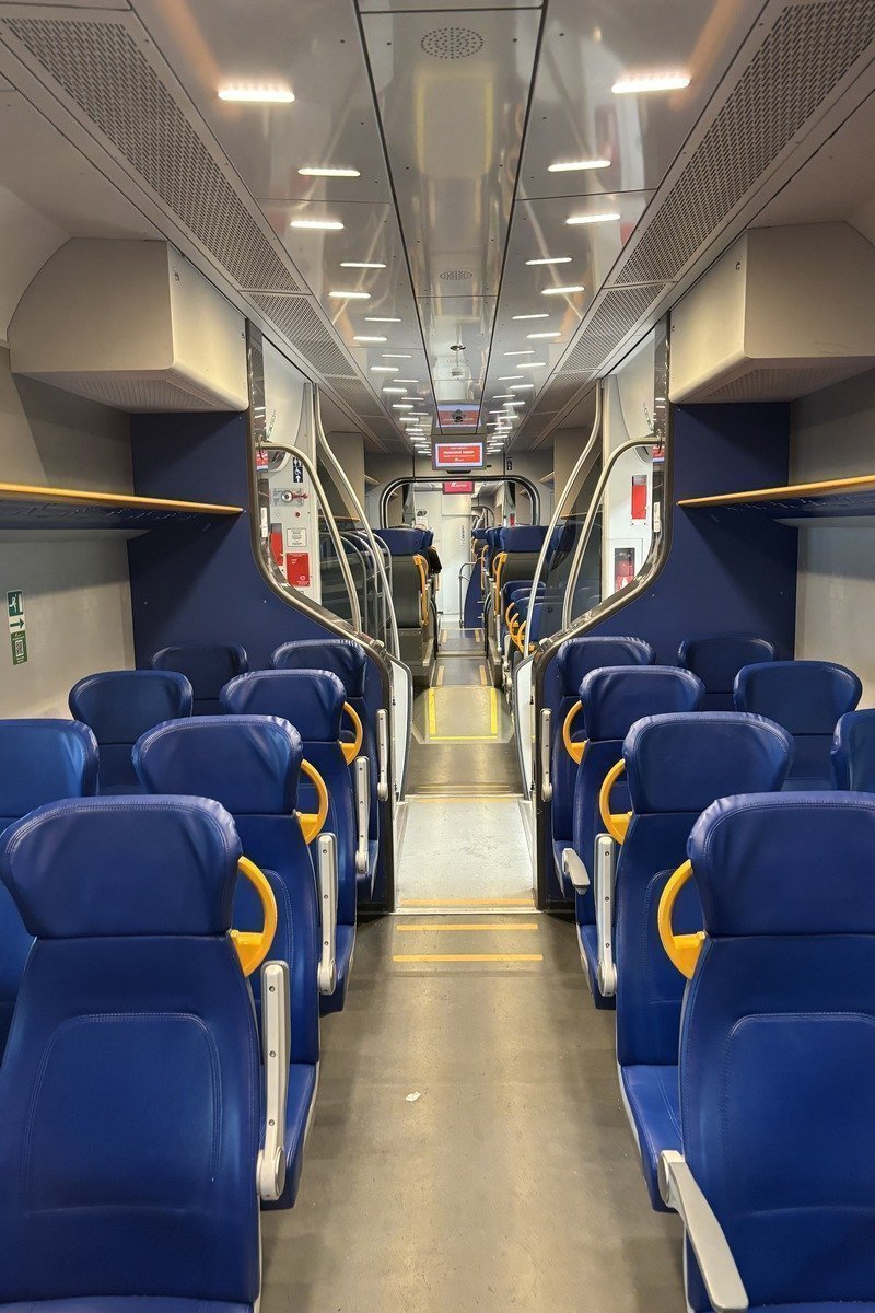 Intérieur vide d'un wagon Leonardo express avec sièges bleus et accoudoirs jaunes
