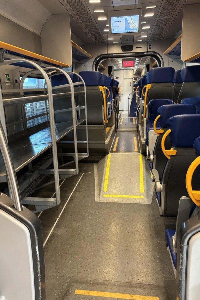 Intérieur d'un wagon de train Leonardo express avec sièges bleus et accoudoirs jaunes
