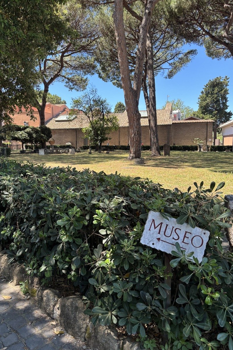 Panneau directionnel museo dans un jardin verdoyant avec bâtiment ocre