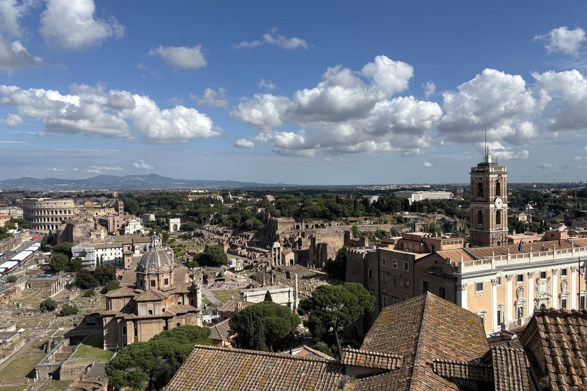 Vue panoramique sur des ruines antiques, clochers et toits de tuiles sous ciel nuageux
