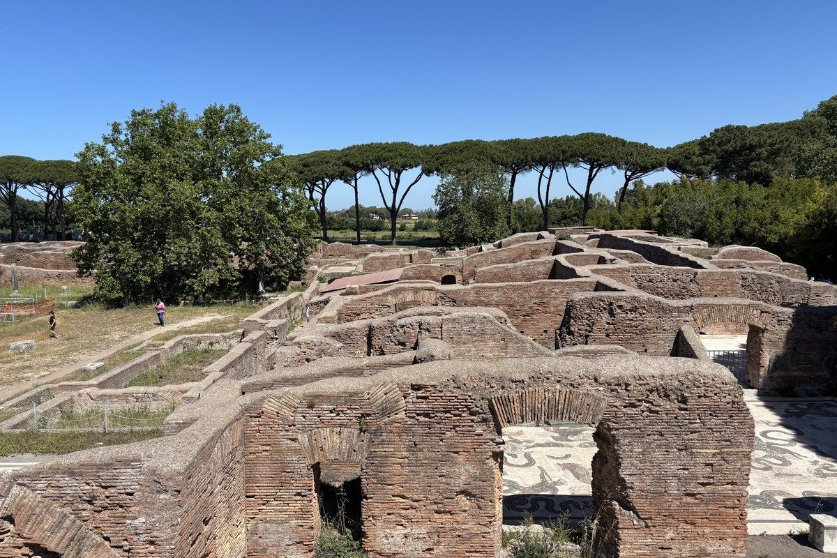 Ruines de murs en briques des Thermes de Neptune avec pins parasols et ciel bleu