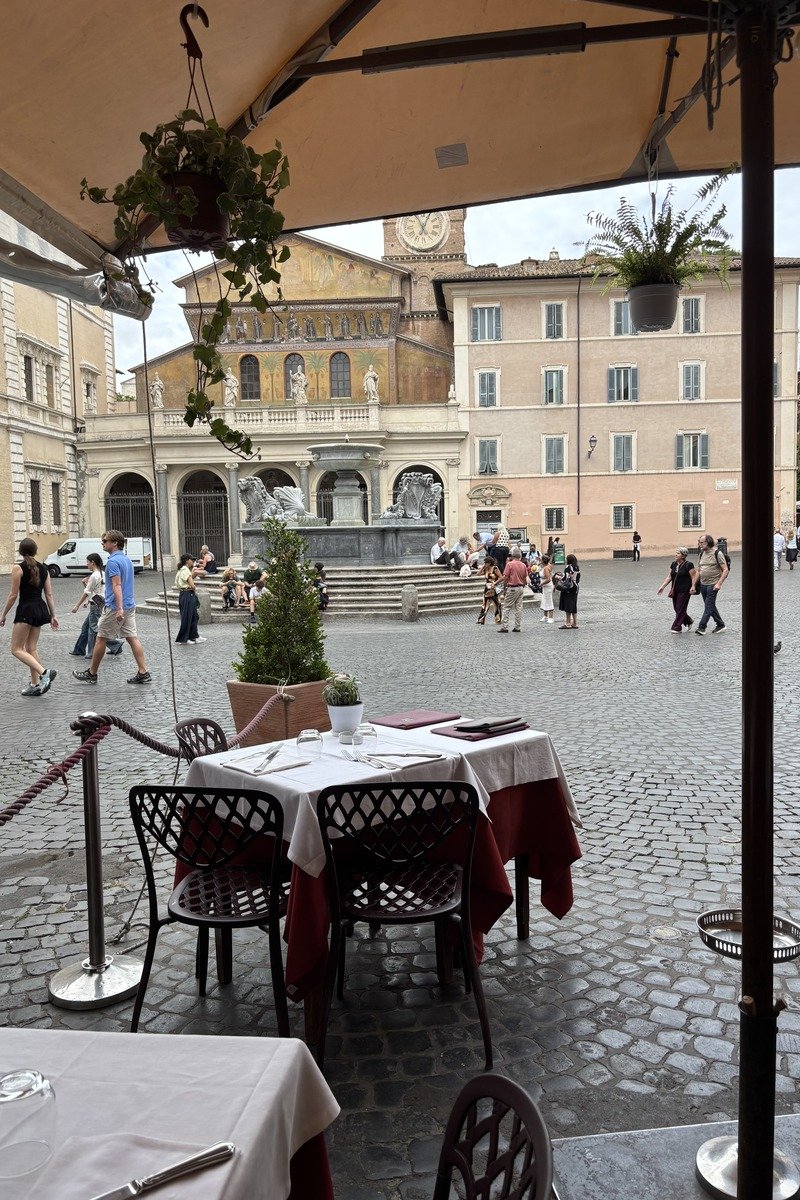 Table de restaurant en terrasse donnant sur la Piazza Santa Maria in Trastevere