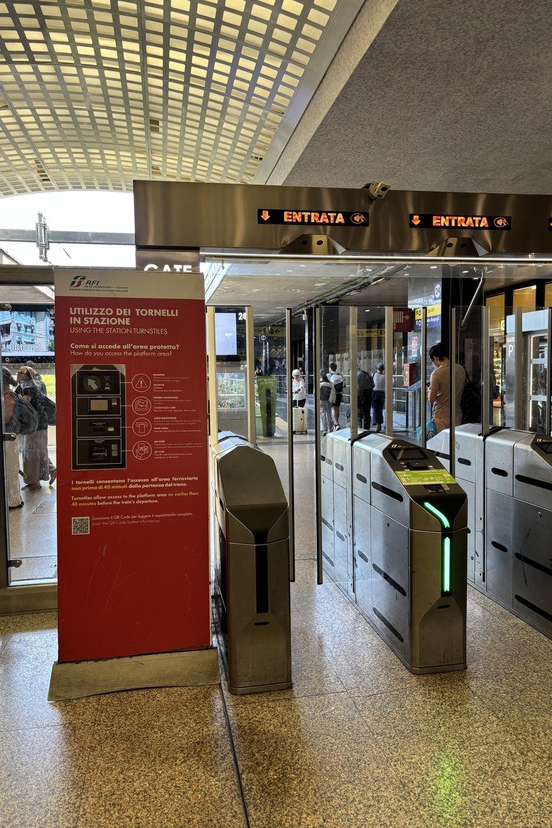 Tourniquets d'accès aux quais de la gare Termini avec panneau d'instructions bilingue
