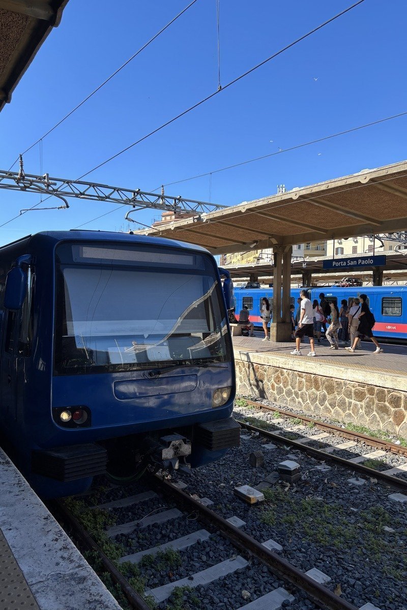 Train bleu en gare de Porta San Paolo avec voyageurs sur le quai couvert