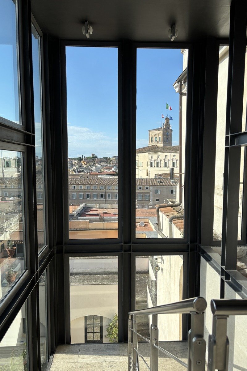 Vue sur les toits depuis une cage d'escalier vitrée avec rampe métallique