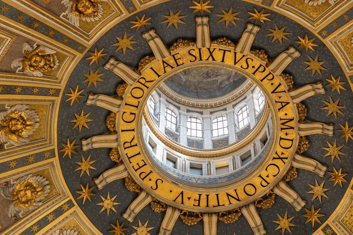 Vue en contre-plongée d'une coupole ornée dorée avec inscription latine