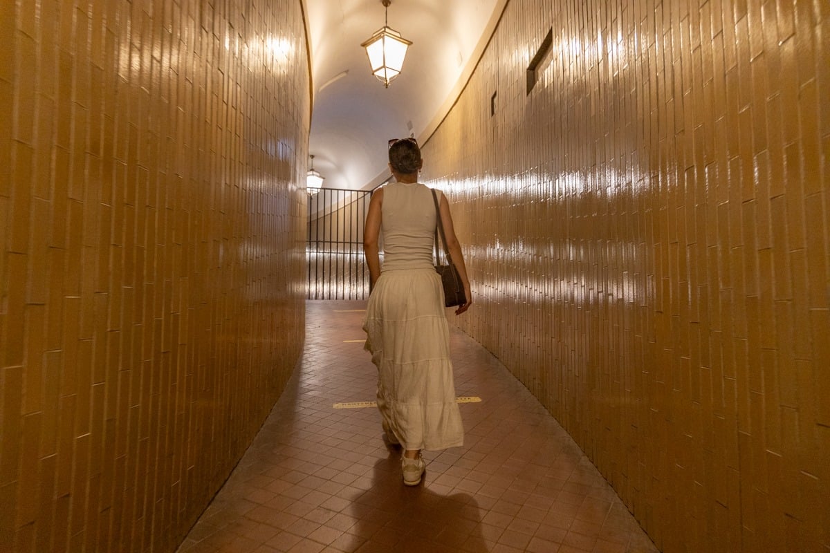 Femme en robe blanche marchant dans un couloir carrelé doré