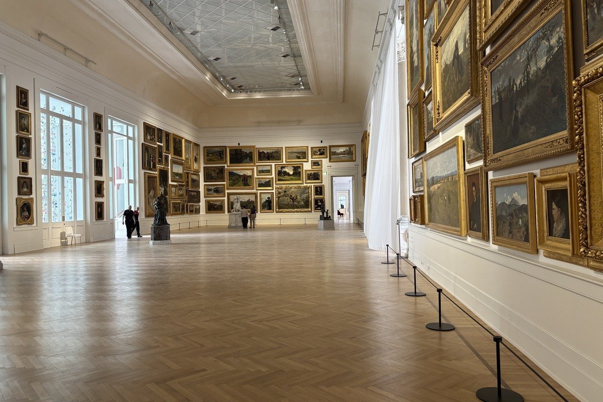 Grande salle de musée avec tableaux aux cadres dorés et parquet