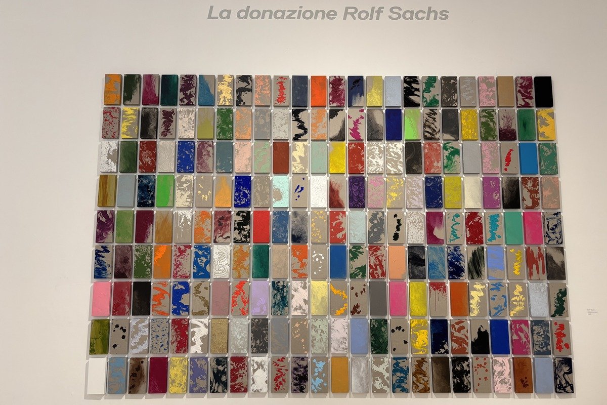 Grille de petites plaques colorées variées accrochées sur mur blanc