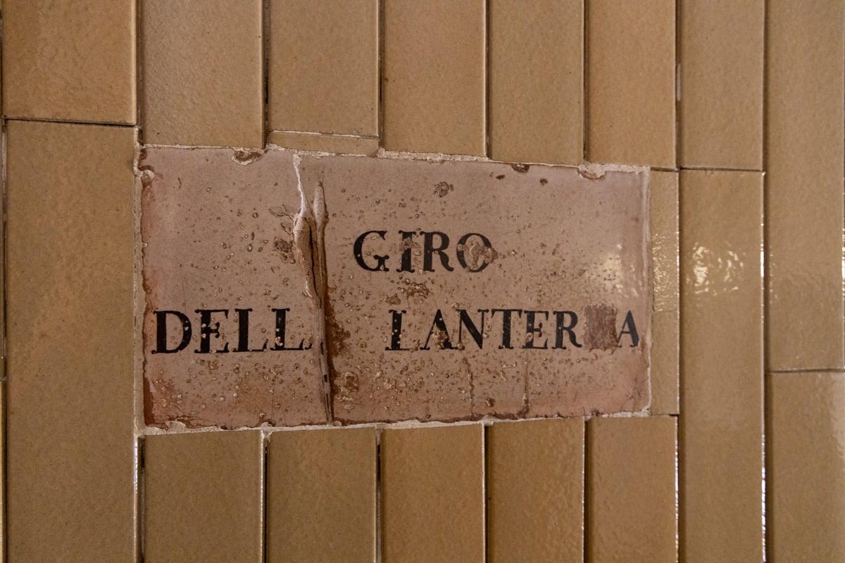 Panneau en céramique ancienne avec inscription noire sur mur de carreaux beiges