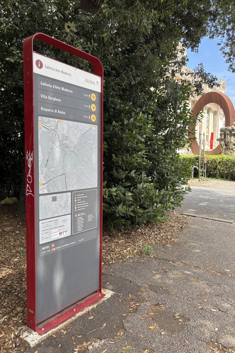 Panneau d'information touristique rouge avec carte et directions vers musées